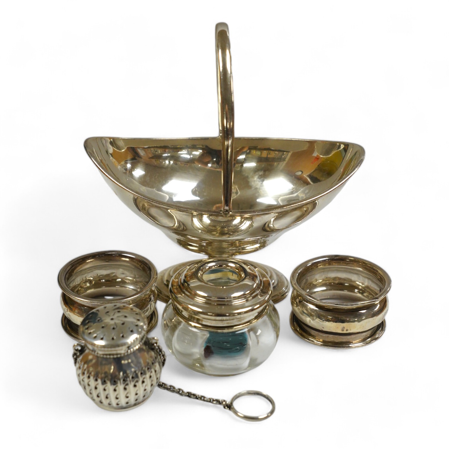 An Edwardian silver boat shaped sugar basket, by Thomas Bradbury & Sons, London, 1905, 13.9cm, together with two silver napkin rings, mounted glass hair tidy and a sterling pomander. Condition - poor to fair